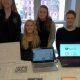 fire elever fremviser designtanker på et bord foran sig og på bærbare computerskærme