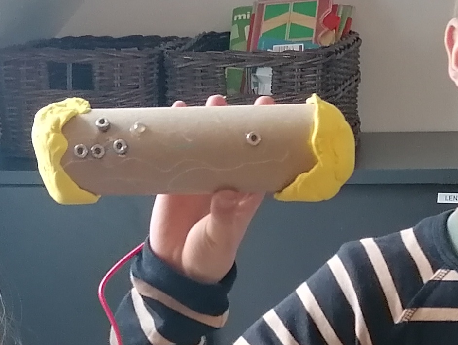 Elev viser controller lavet af et køkkenrullerør med gult modellervoks i enderne