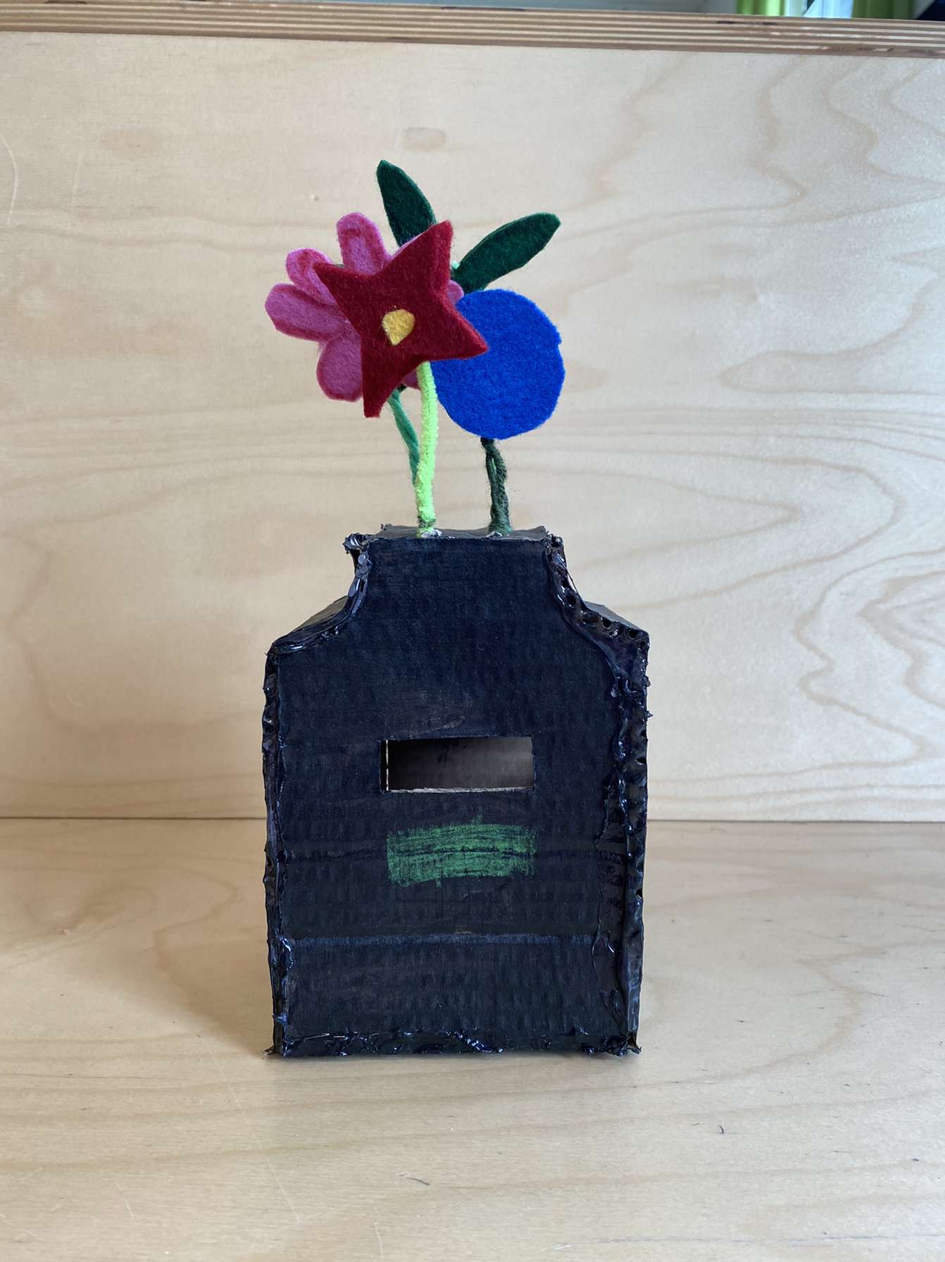 Elev har skabt en mockup af pap- en skraldespand, hvor der vokser blomster på toppen
