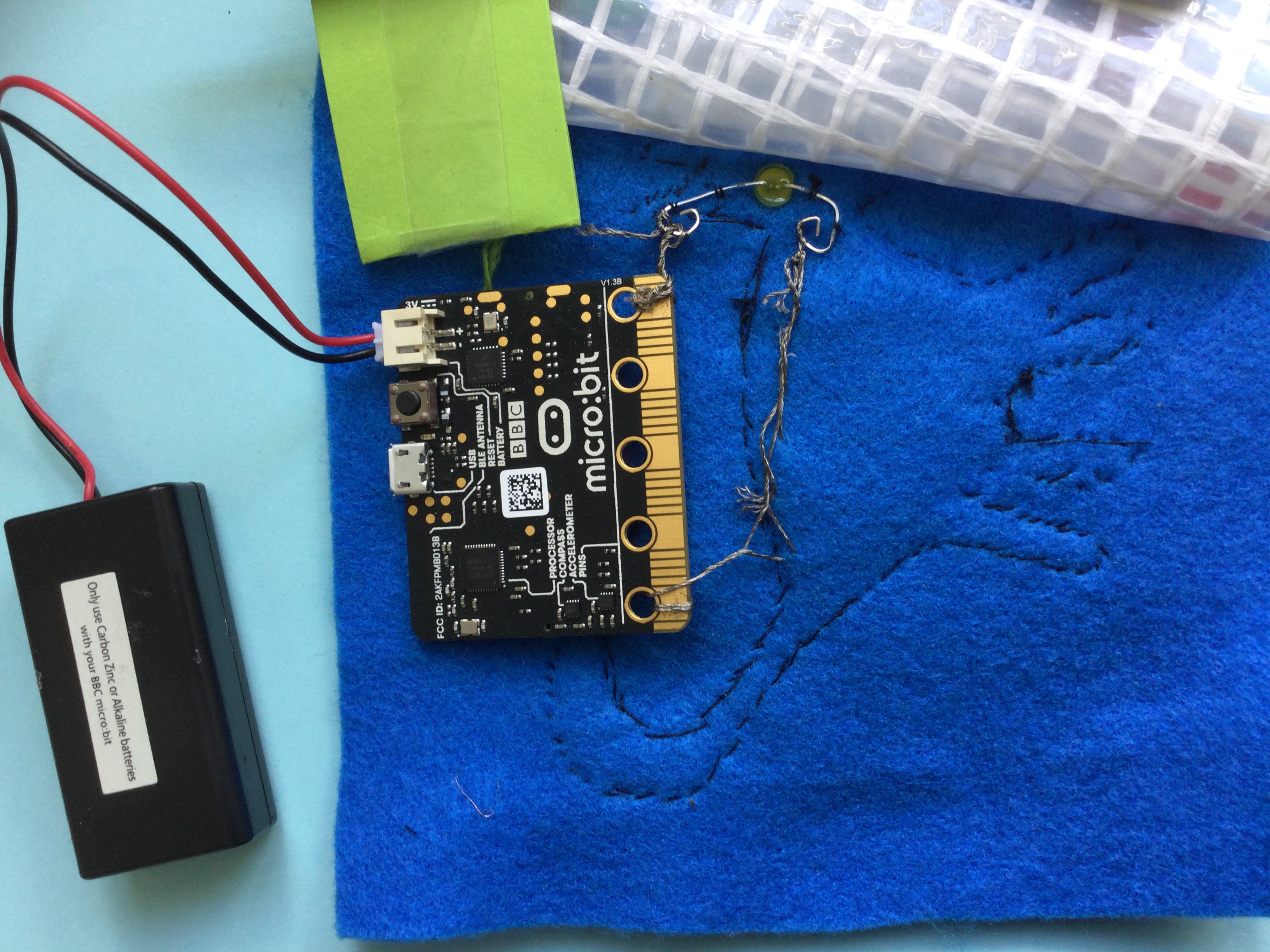 Microbit forbundet med batteri og diode i lomme på taske